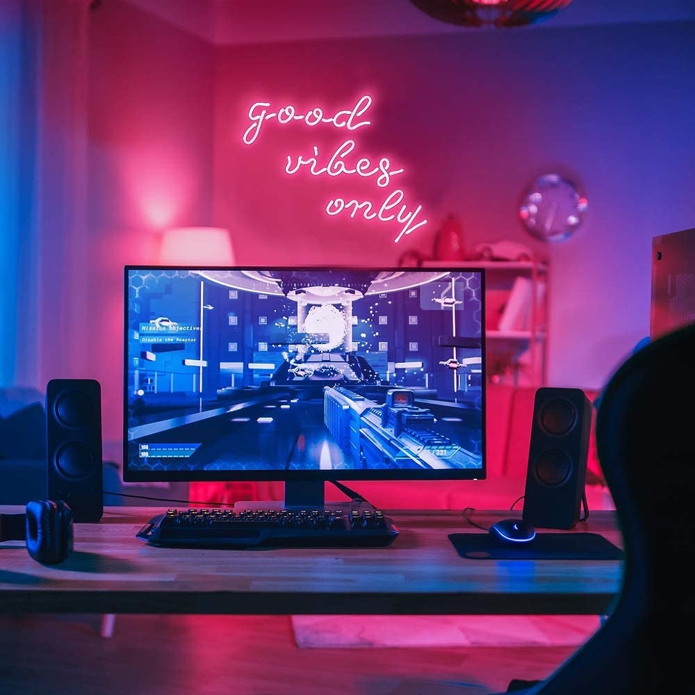 &quot;Good Vibes Only&quot; neon pink sign above wall near desk in living room