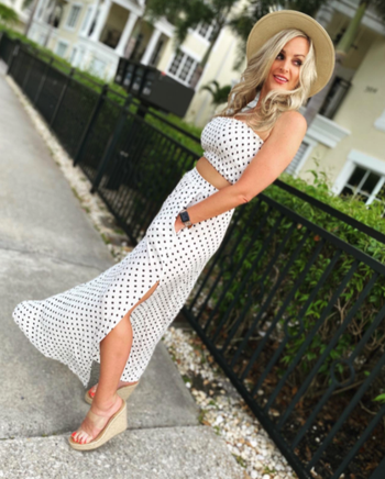 reviewer wearing white and black polka dot strapless crop top and skirt with wedges