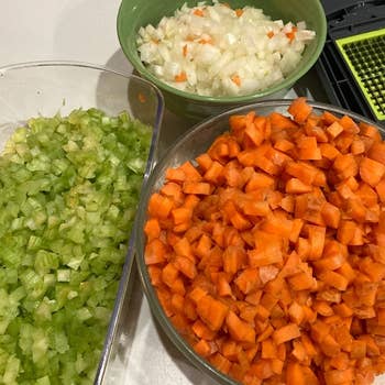 a reviewer photo of several bowls filled with different chopped vegetables sitting next to the chopper unit 
