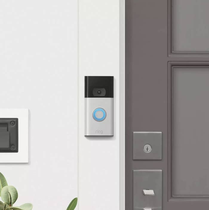 The Ring doorbell has a black top portion with a camera while the rest is silver with a blue circle and the word &quot;ring&quot;