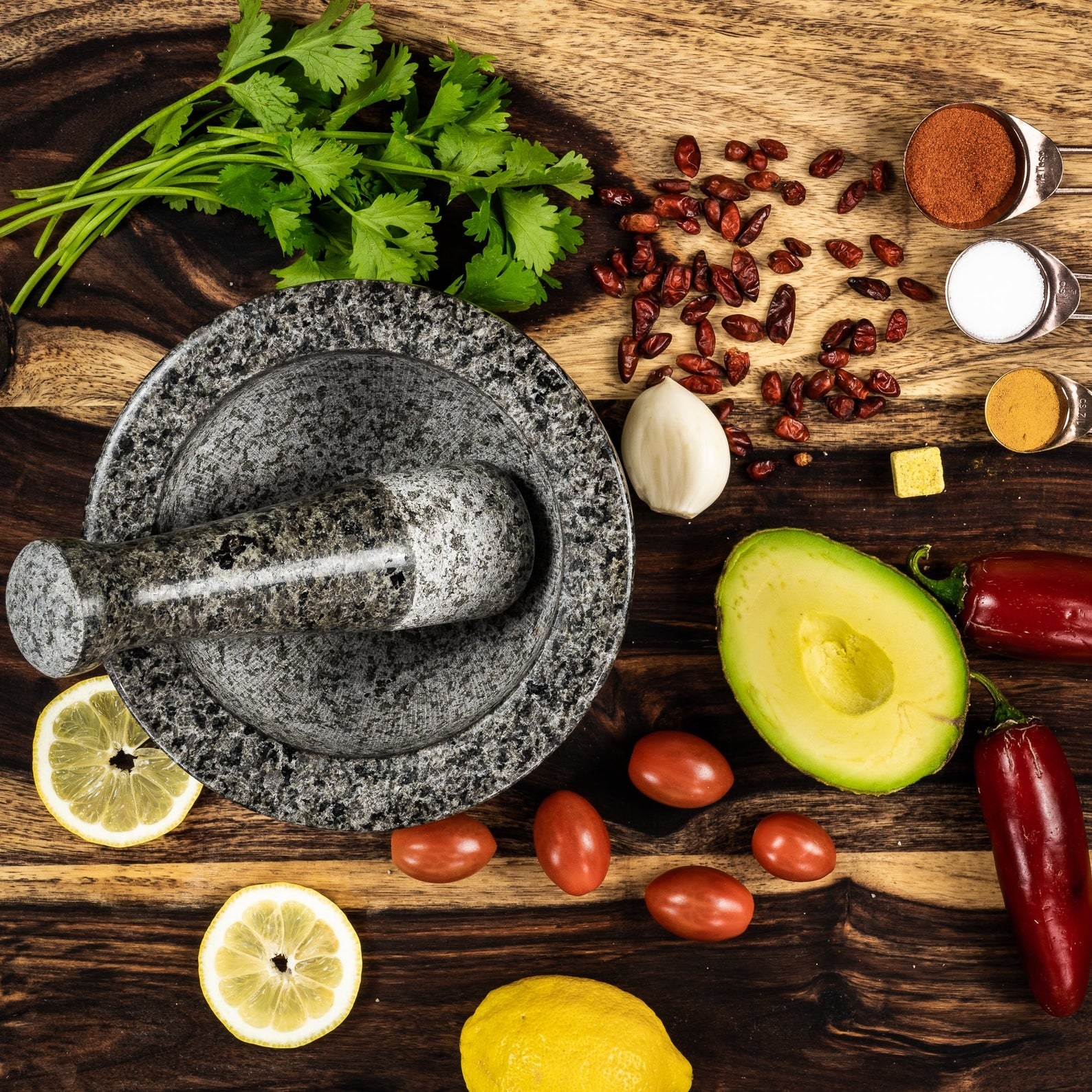 A stone mortar and pestle set on a table with ingredients 