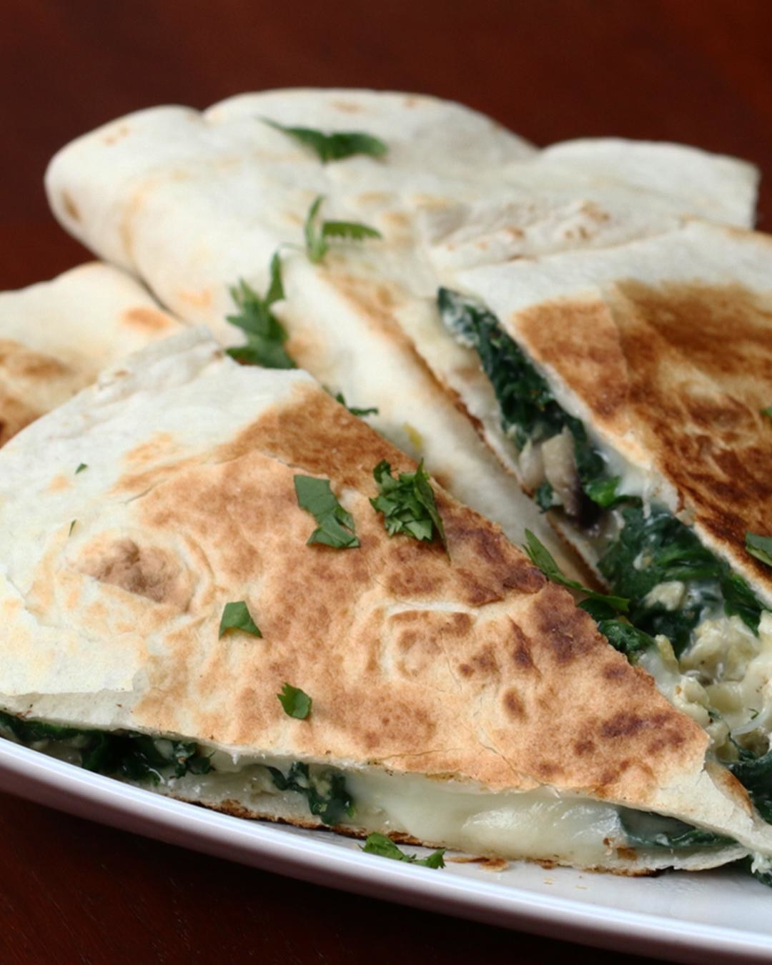 A cheesy quesadilla with spinach and mushroom.