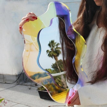 A person holds the mirror outside to show off its array of colors