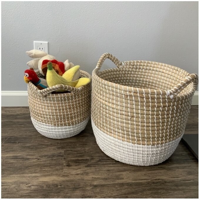 The baskets, which have a white woven bottom and a light brown woven top, are round, and have two round handles for carrying extending from the top edge of the basket