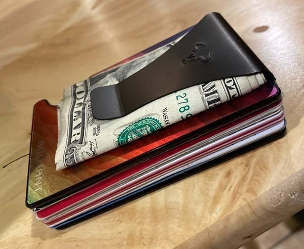 A reviewer shows off their wallet with cards in it and money in the clip