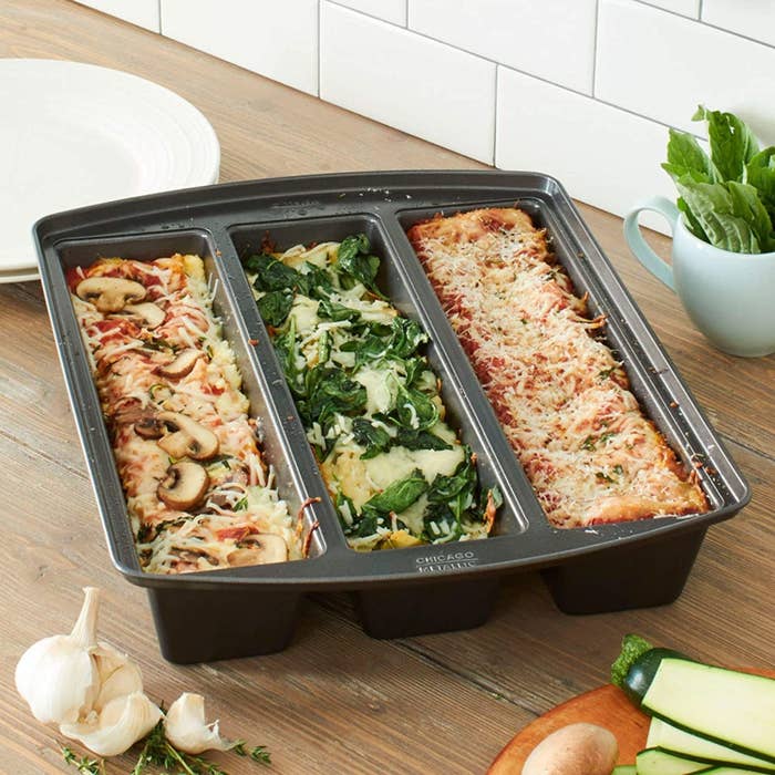 The pan with three rectangles of cooked lasagna with different ingredients in it 