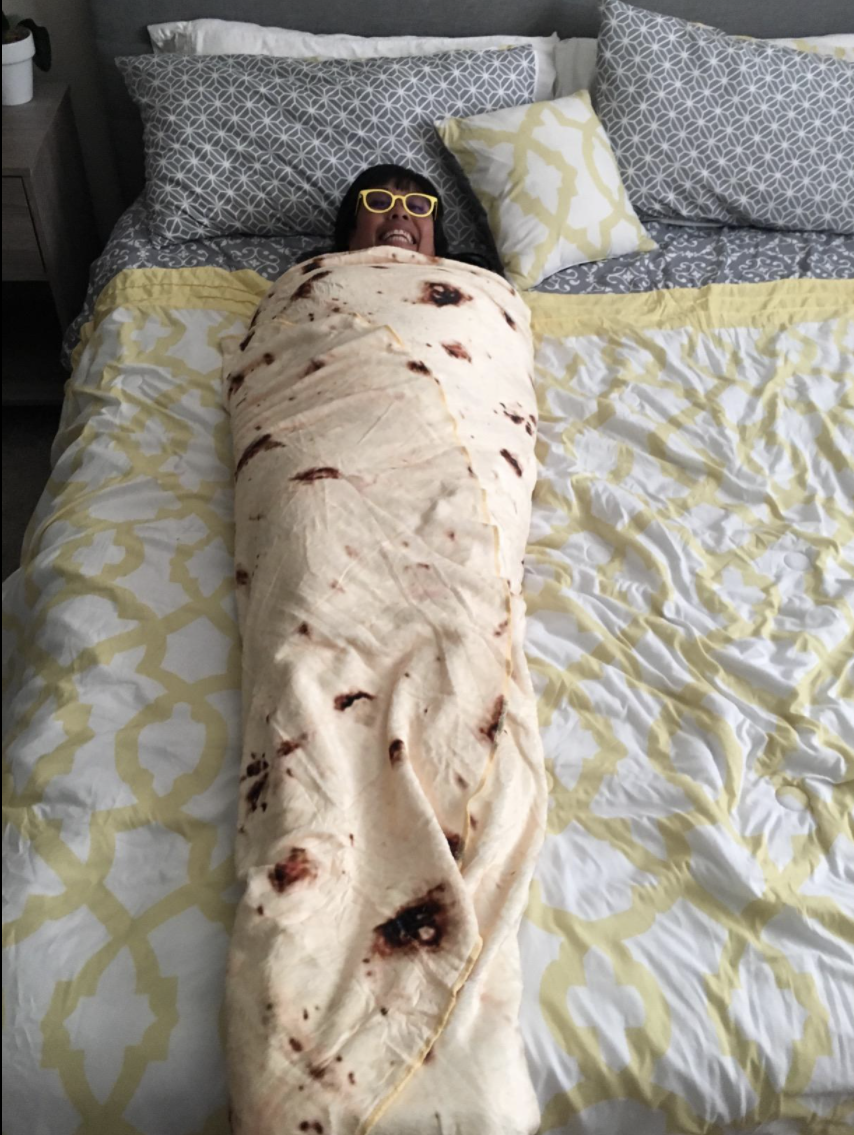 Reviewer is on a bed is wrapped in the tortilla blanket