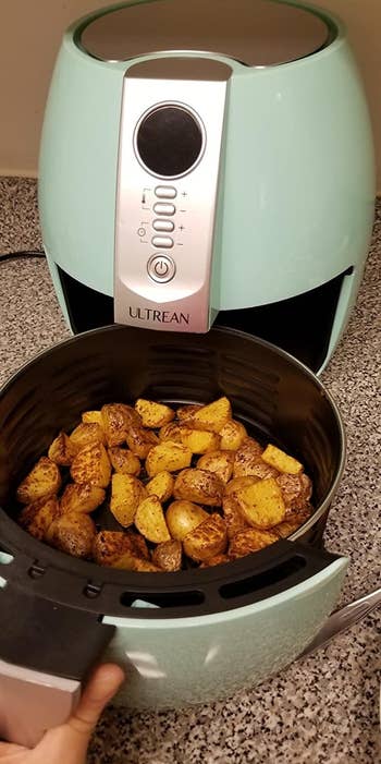 a reviewer photo of the open air fryer filled with potatoes 