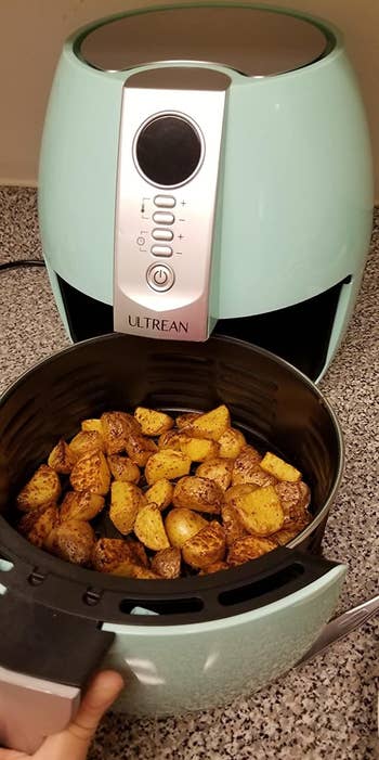 a reviewer photo of the open air fryer filled with potatoes 