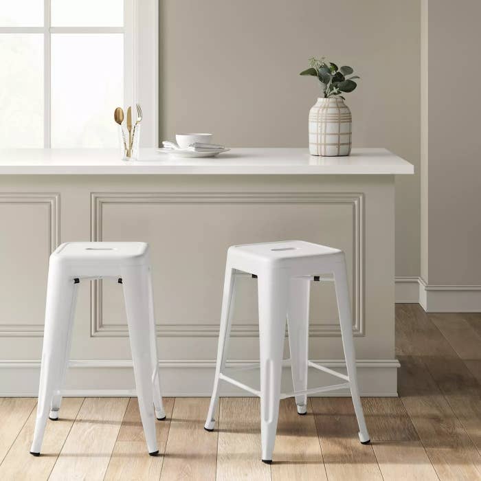 two white barstools in front of a kitchen island