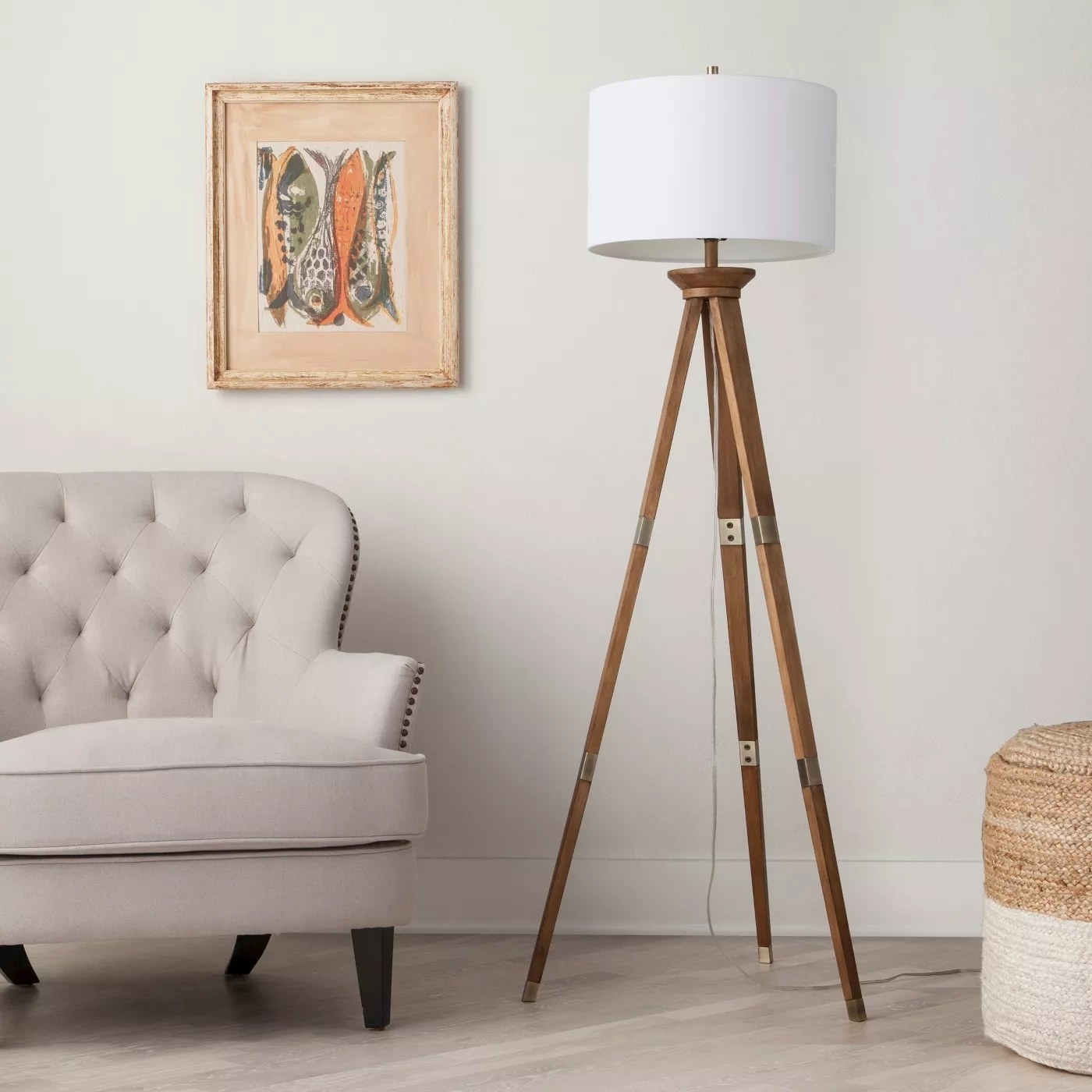 The tripod lamp with wooden legs and brass accents in a living room