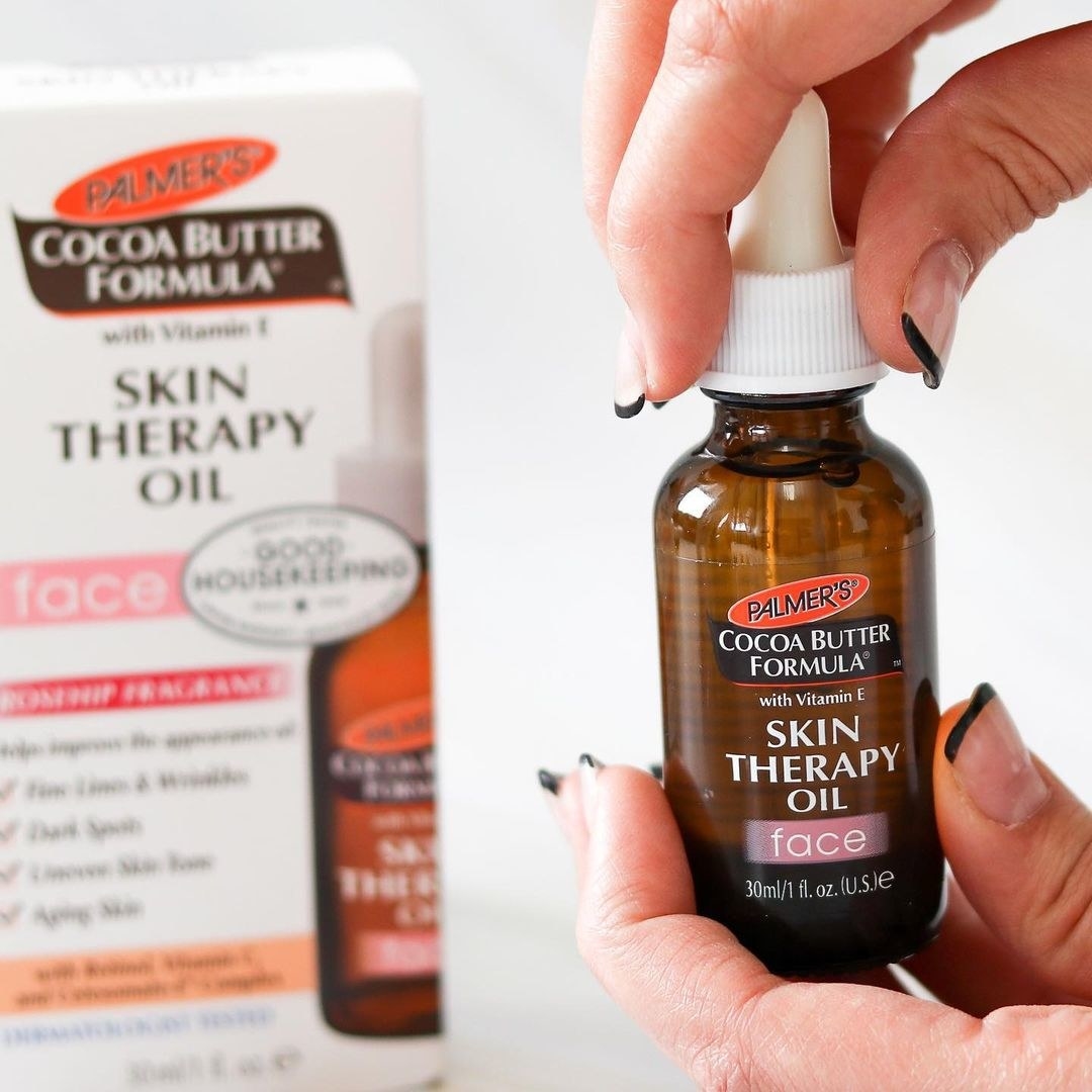 Hand holding bottle of Palmer&#x27;s Skin Therapy oil