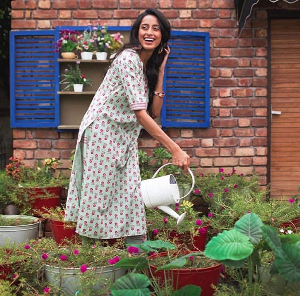A person wearing the kurta and watering their plants.