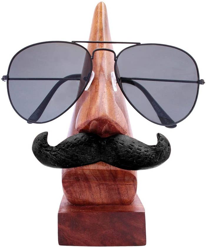 A spectacle holder with spectacles on it shaped like a nose and a moustache on it.