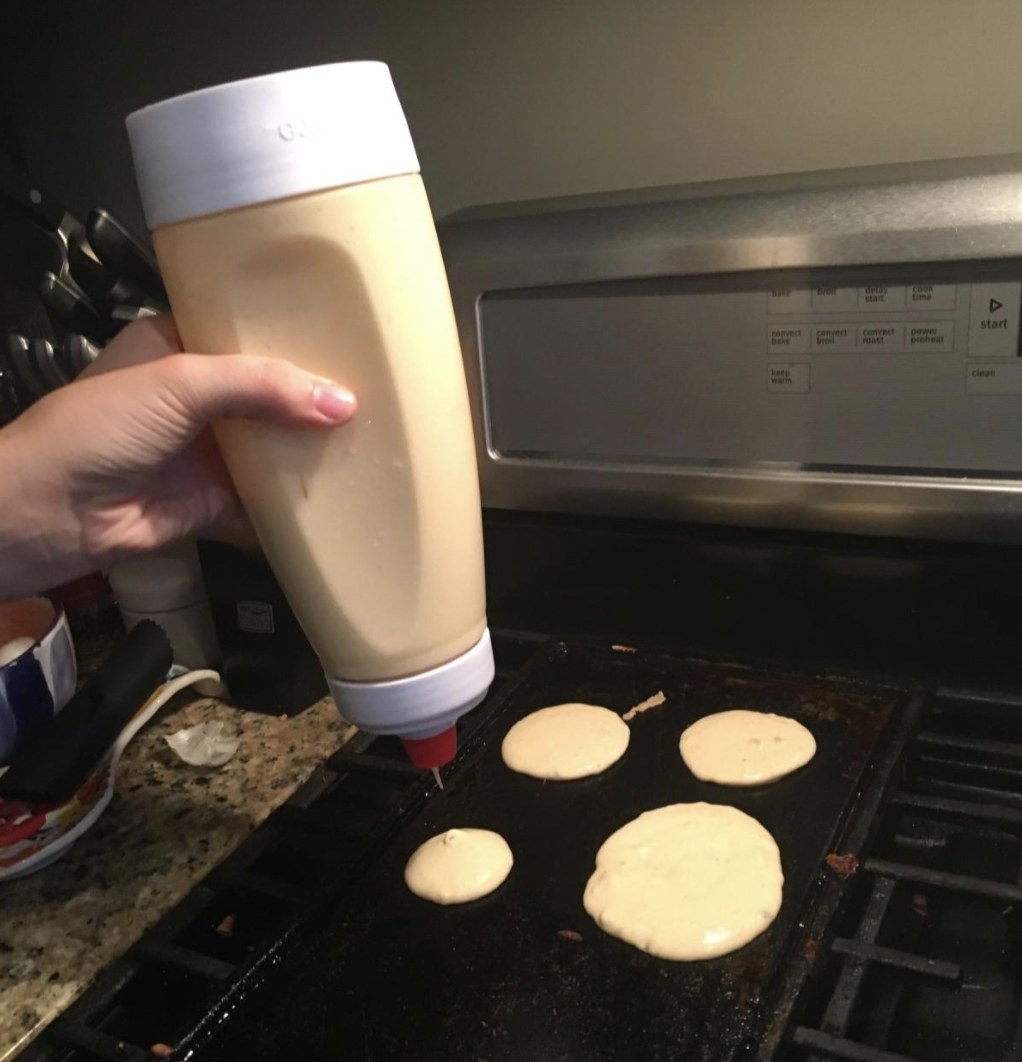 A person squeezing pancake batter out of mixer
