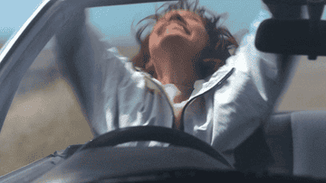 A person swaying their arms up in a car