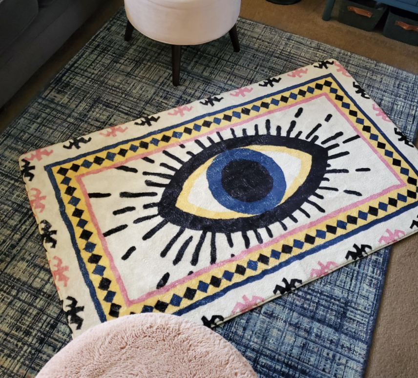 Reviewer's rug with an eye illustration is displayed on the floor