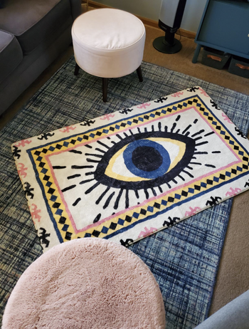 Reviewer's rug with an eye illustration is displayed on the floor