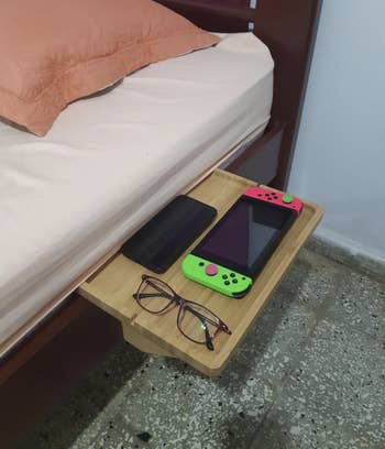 reviewer's shelf attached to the side of their bed with a GameBoy, eyeglasses, and a phone