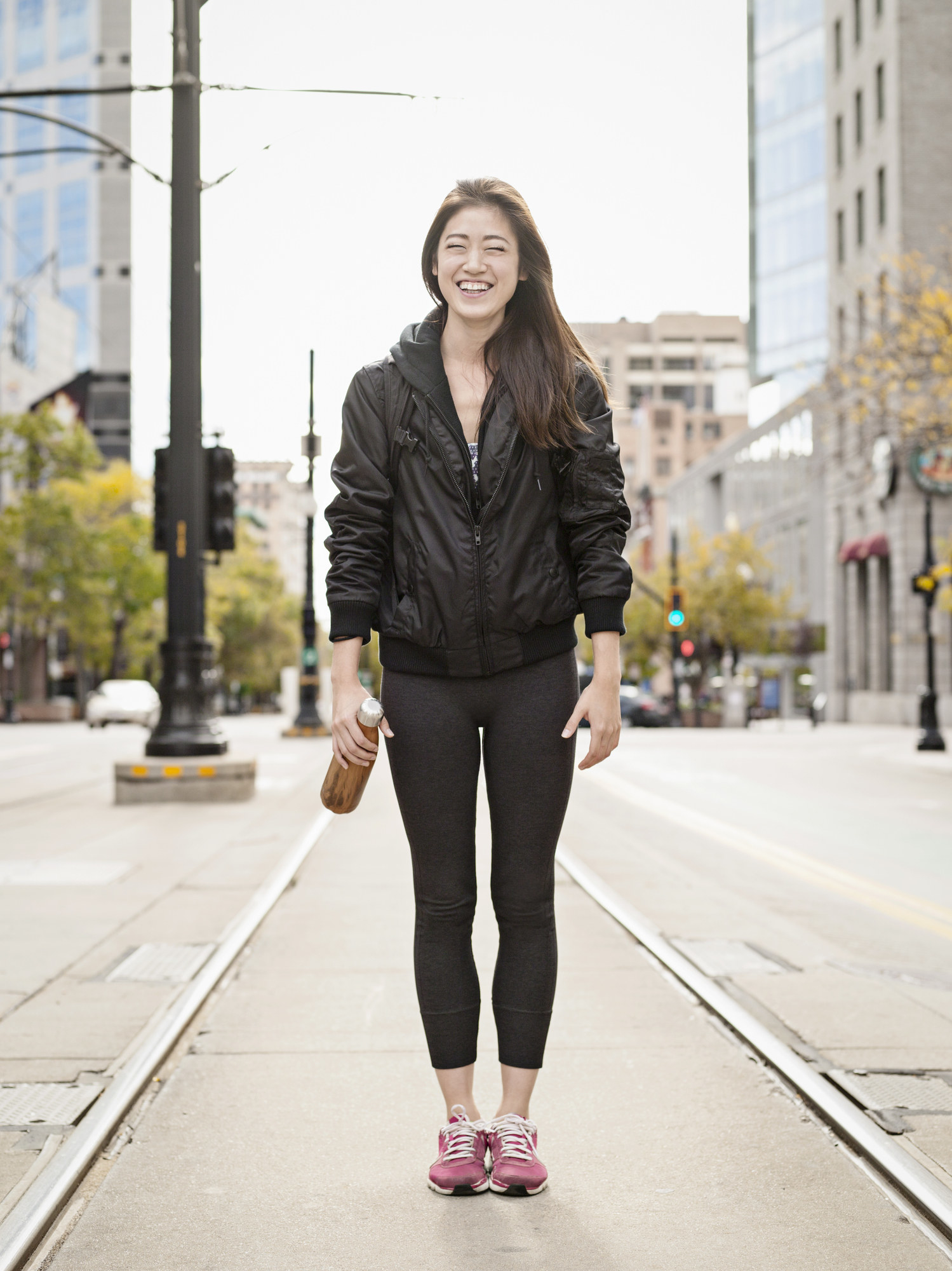 一个女人穿着紧身裤和一件夹克站在大街上