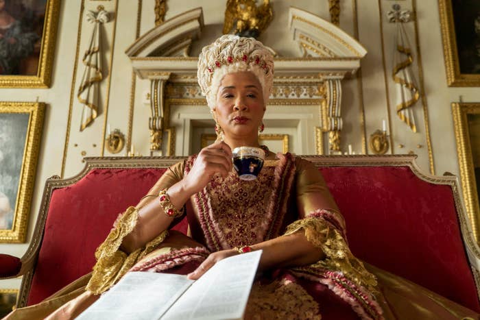 Queen Charlotte sitting, sipping tea, and reading