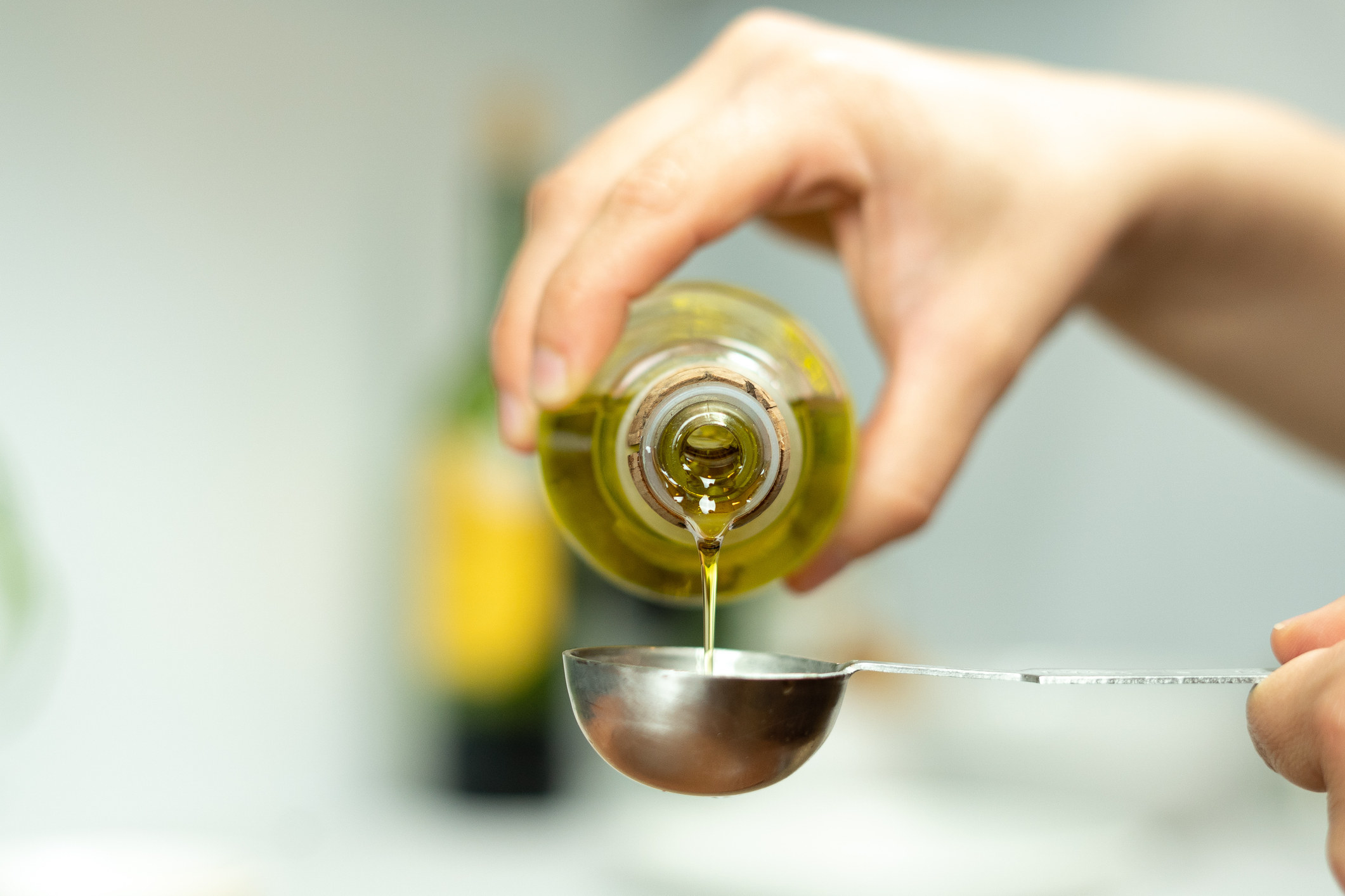 Measuring olive oil into a spoon