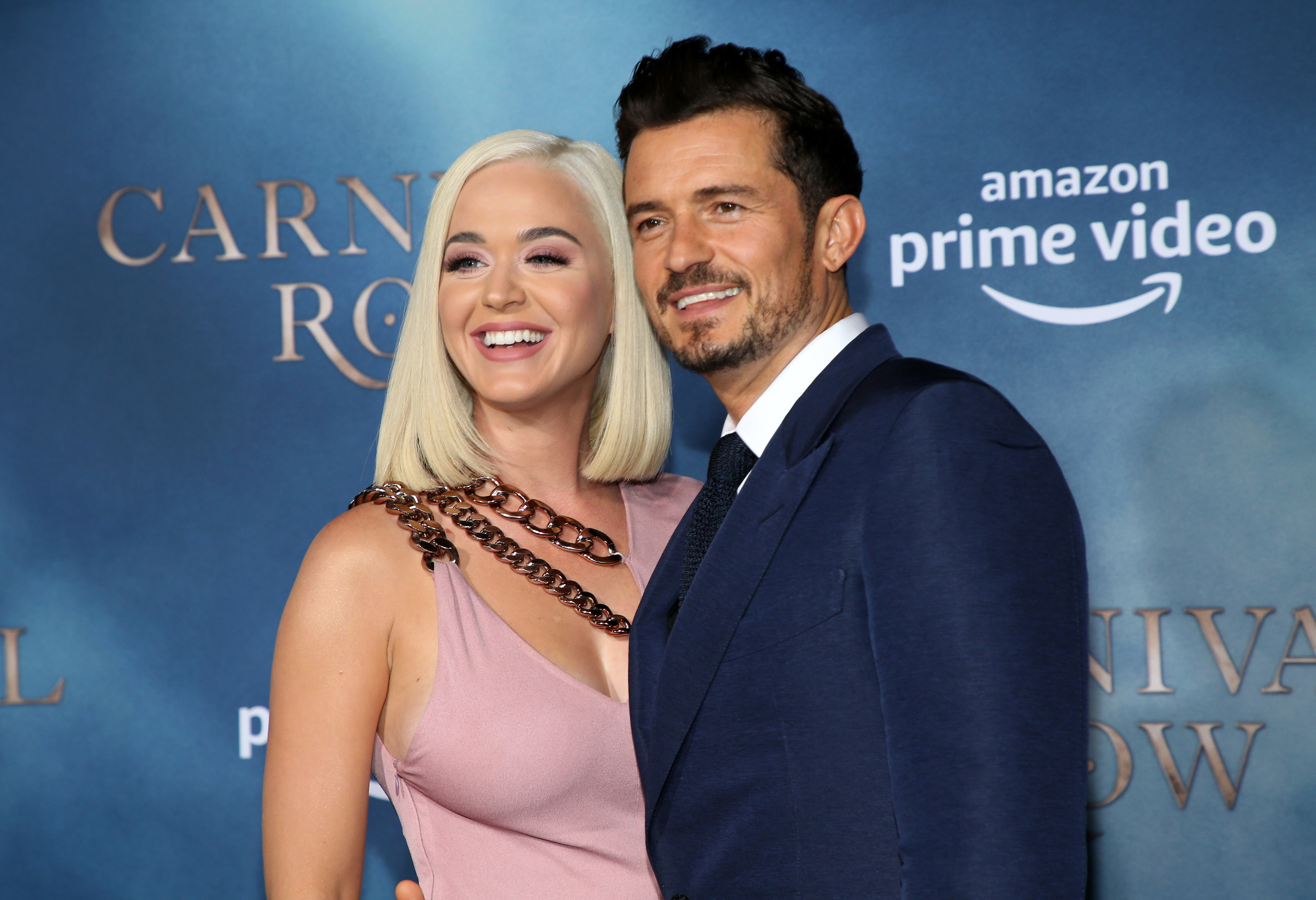 Katy and Orlando smile while posing on a red carpet