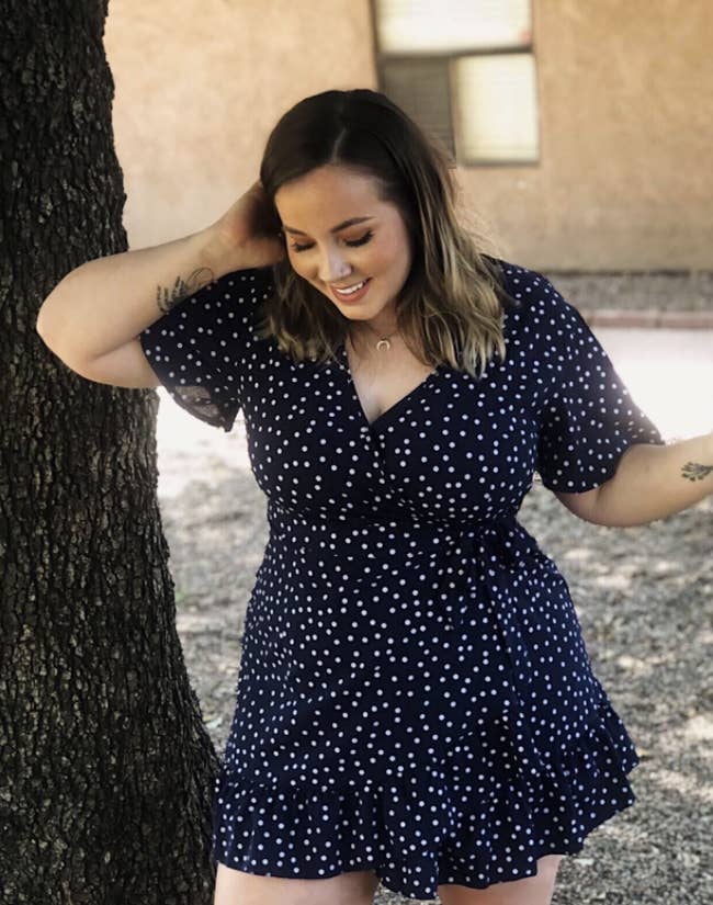 reviewer wearing short sleeve V-neck dress in a polka dot print with ruffle at the hem