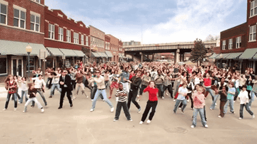 A large group of people doing a choreographed dance in a town