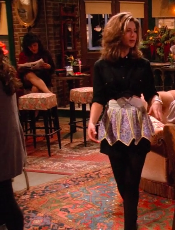 Rachel wearing tights, a miniskirt, an apron, and a long-sleeve button-up tied to be a crop top
