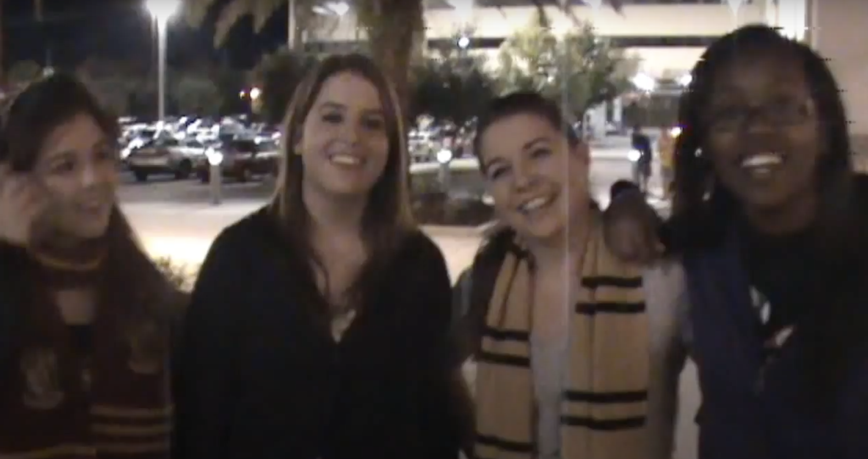 Four friends wearing &quot;Harry Potter&quot; scarves smile while waiting to get into the movie theater