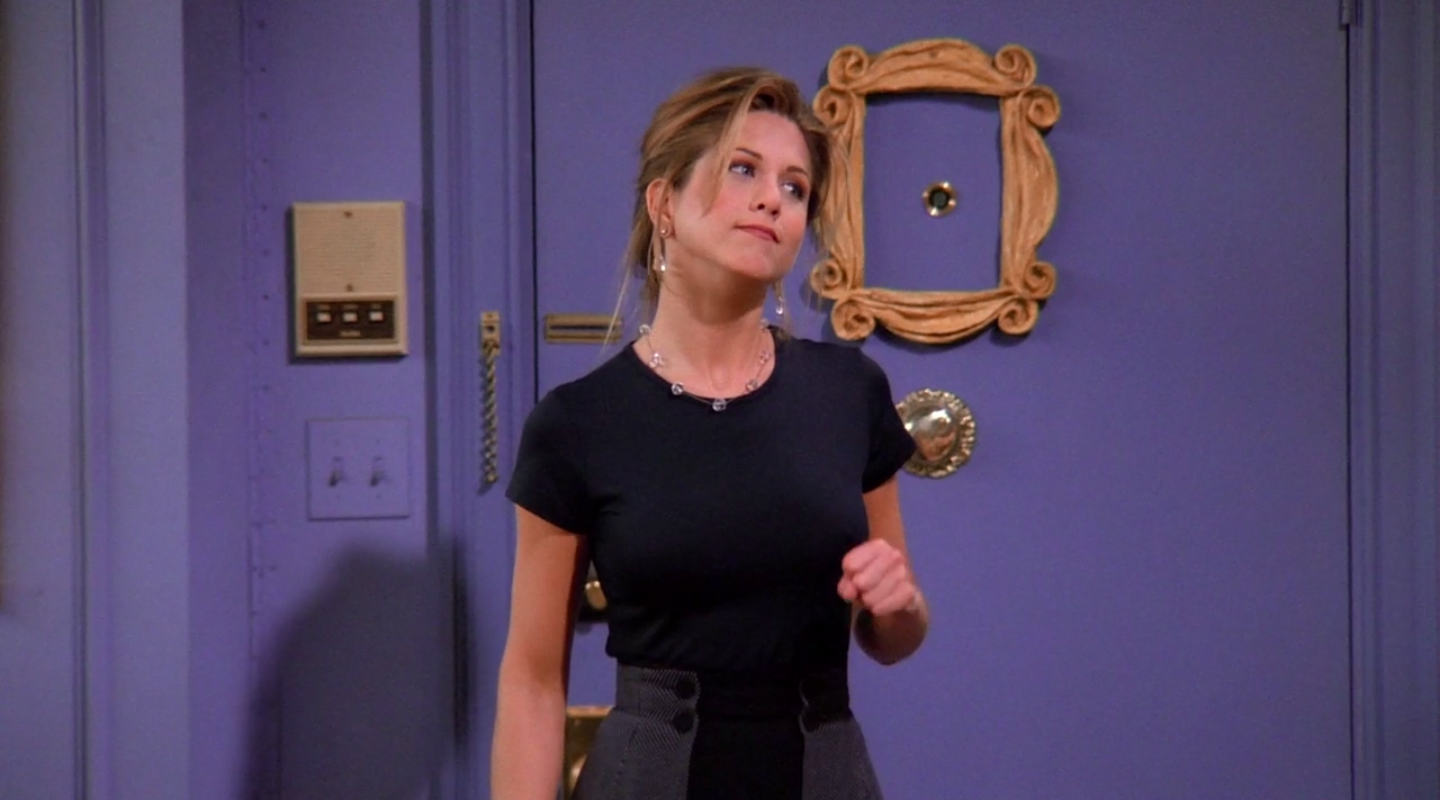 Rachel wearing a short-sleeve shirt and a mini skirt with an attached cape