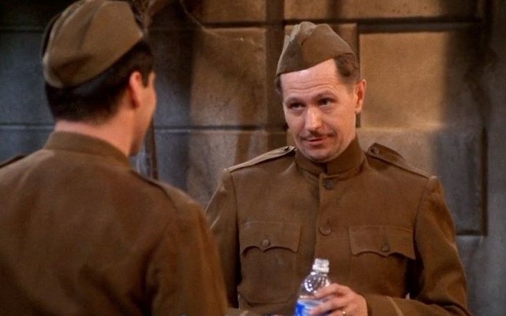 Gary Oldman holds a water bottle and wears a World War I uniform as Richard