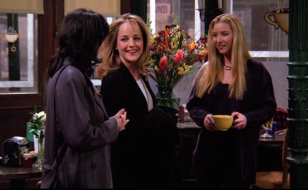 At Central Perk, Phoebe holds a coffee cup in her hand and looks at Jamie, who&#x27;s smiling at Monica