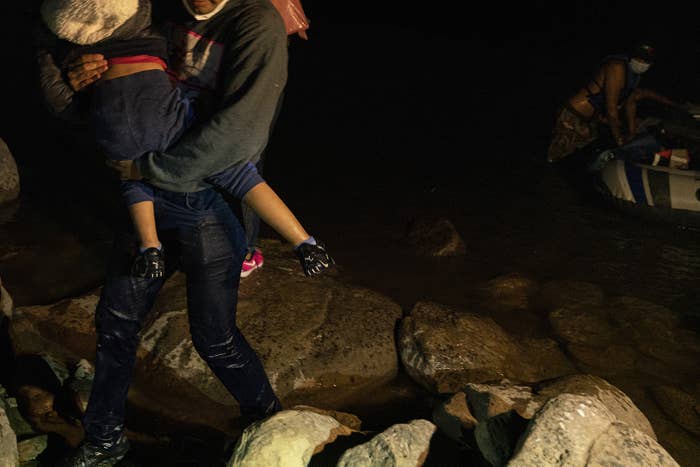 A man standing in the water carries a child