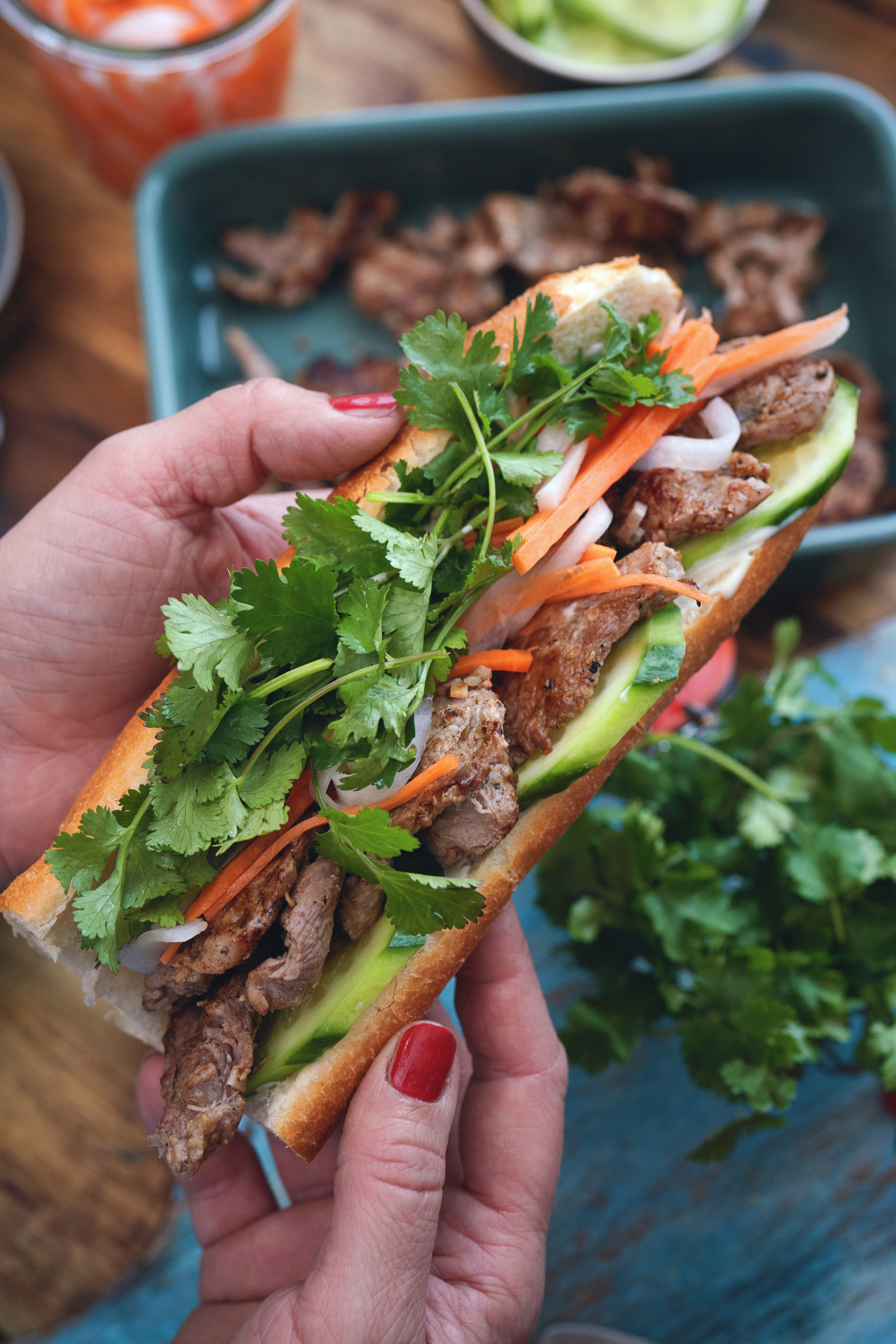 Manicured hand holding a banh mi