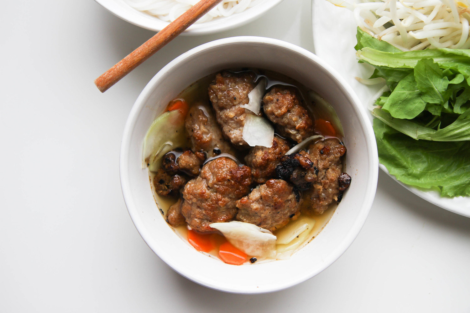 Plain bowl filled with pork patties, broth, and vegetables