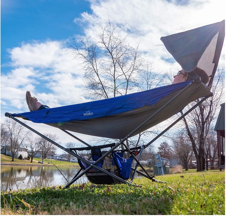 A blue and grey portable, foldable hammock with sun shade umbrella and storage compartment at its base