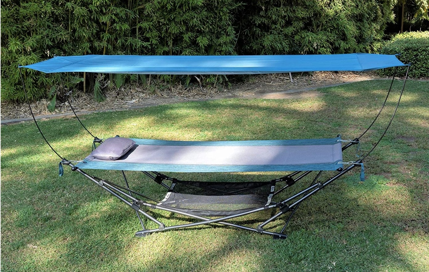 A teal, collapsible, portable canopy hammock on a lawn