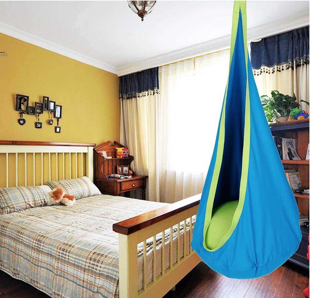 A kids pod, blue and green hammock hanging in a bedroom