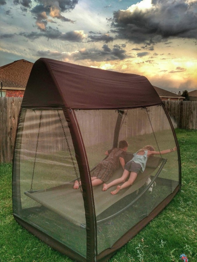 Two models inside the canopy, swing hammock with a protective mosquito net outdoors on the lawn