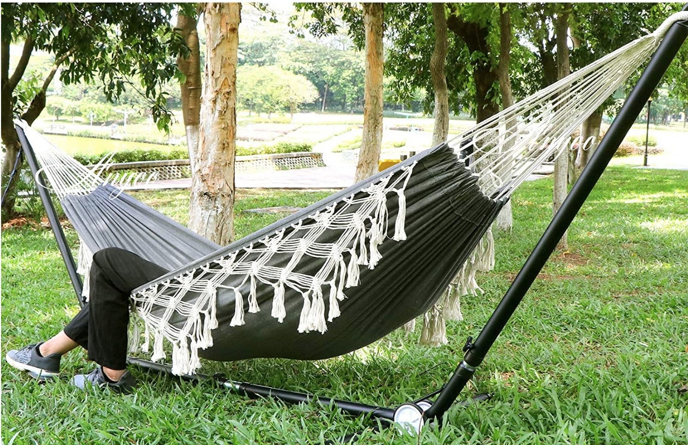 A model inside a black, portable hammock with hanging tassels 
