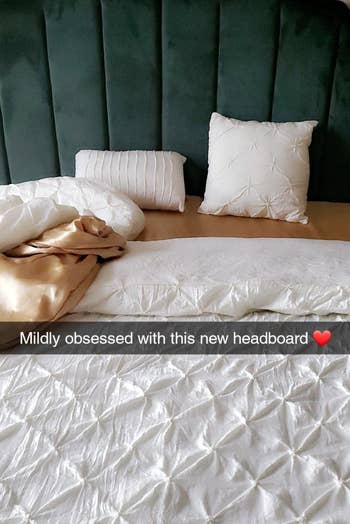 a reviewer photo of their velvet headboard in a deep green that has text written over it that reads mildly obsessed with this new headboard