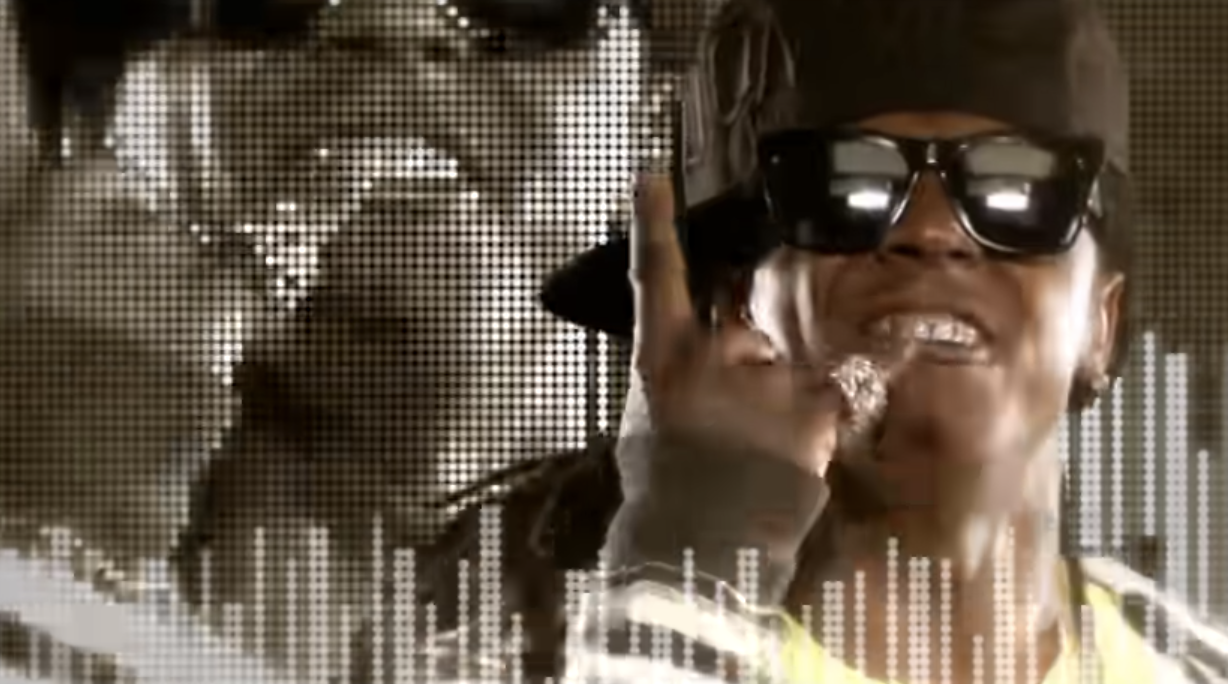 Lil Wayne in sunglasses and a hat pointing up