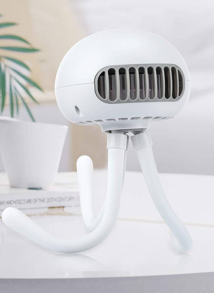 A portable fan with flexible legs perched on a countertop