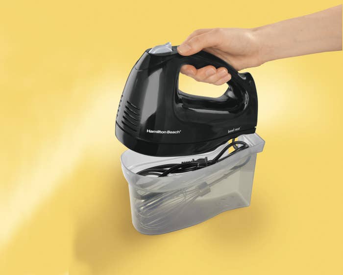 Model holding black hand mixer and putting it in snap-on case
