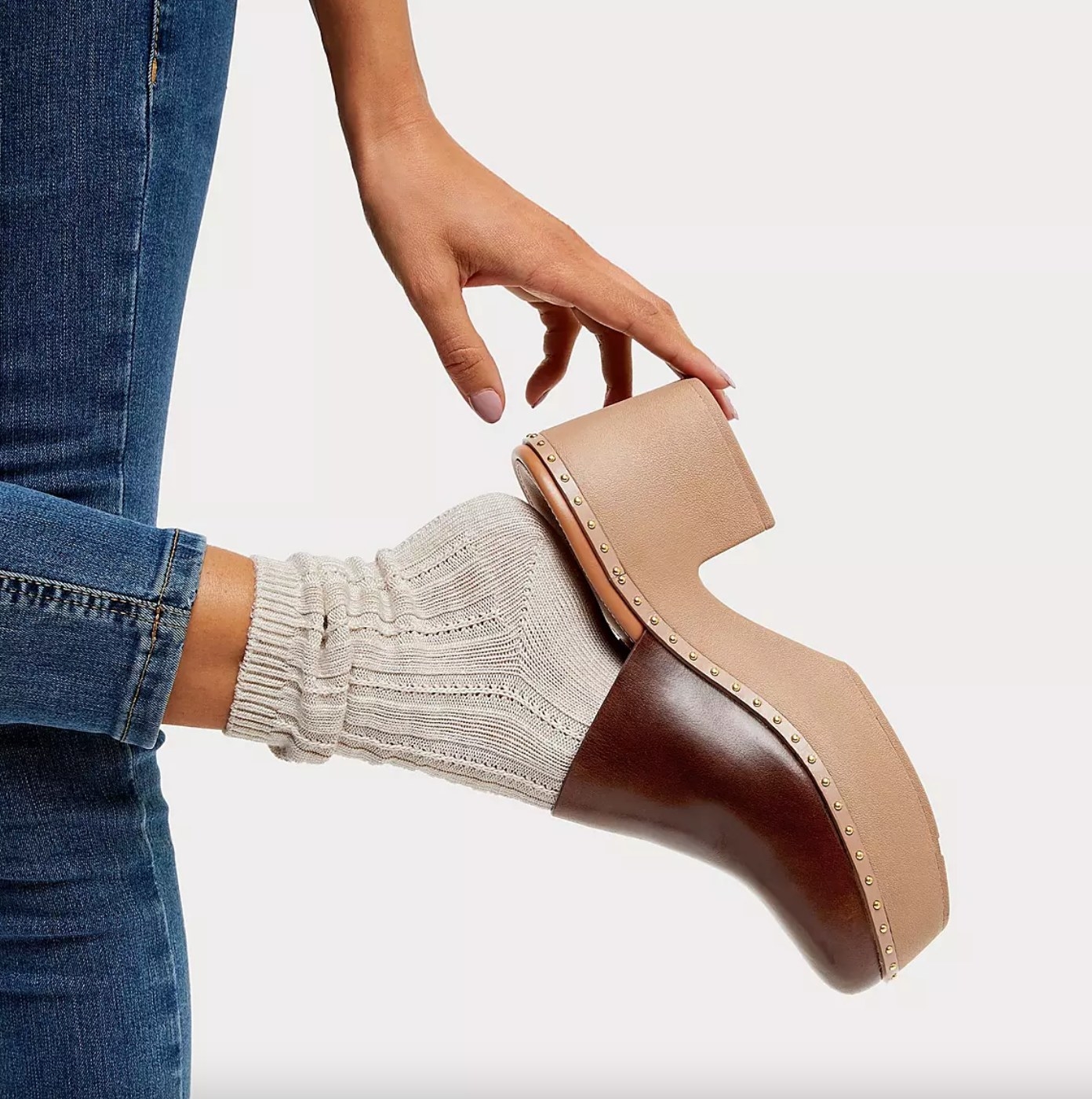 The pair of leather mule platforms in chocolate brown on a model wearing knit socks