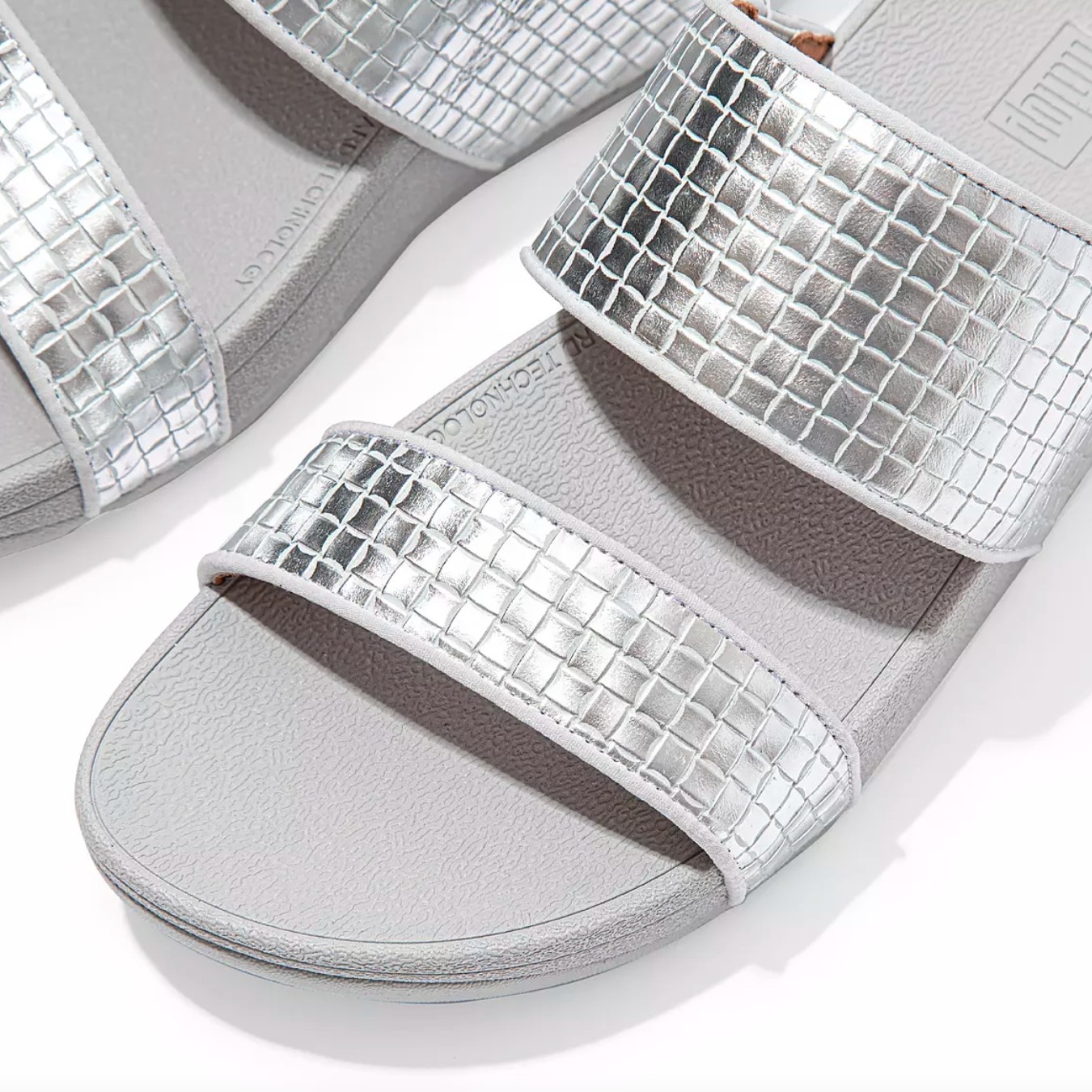 The pair of metallic leather slides in silver
