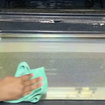 Model wiping off Oven Scrub from clean oven door