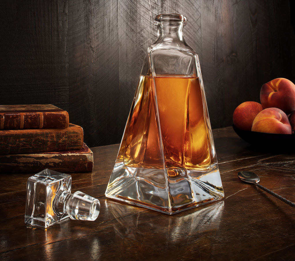 the decanter with a brown liquor in it and lid lying next to bottle